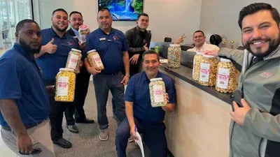 A group of adults holding branded kettle corn jars at an indoor counter.